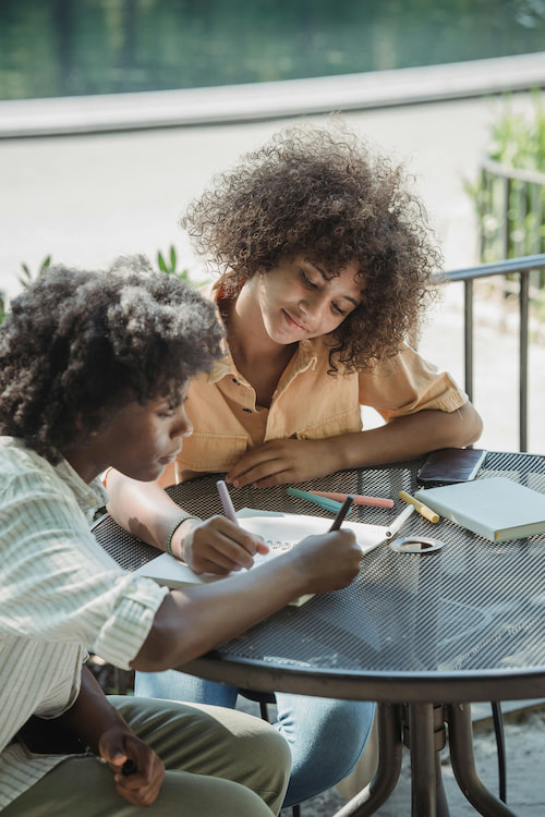 Children drawing and coloring together at an outdoor table on a sunny day